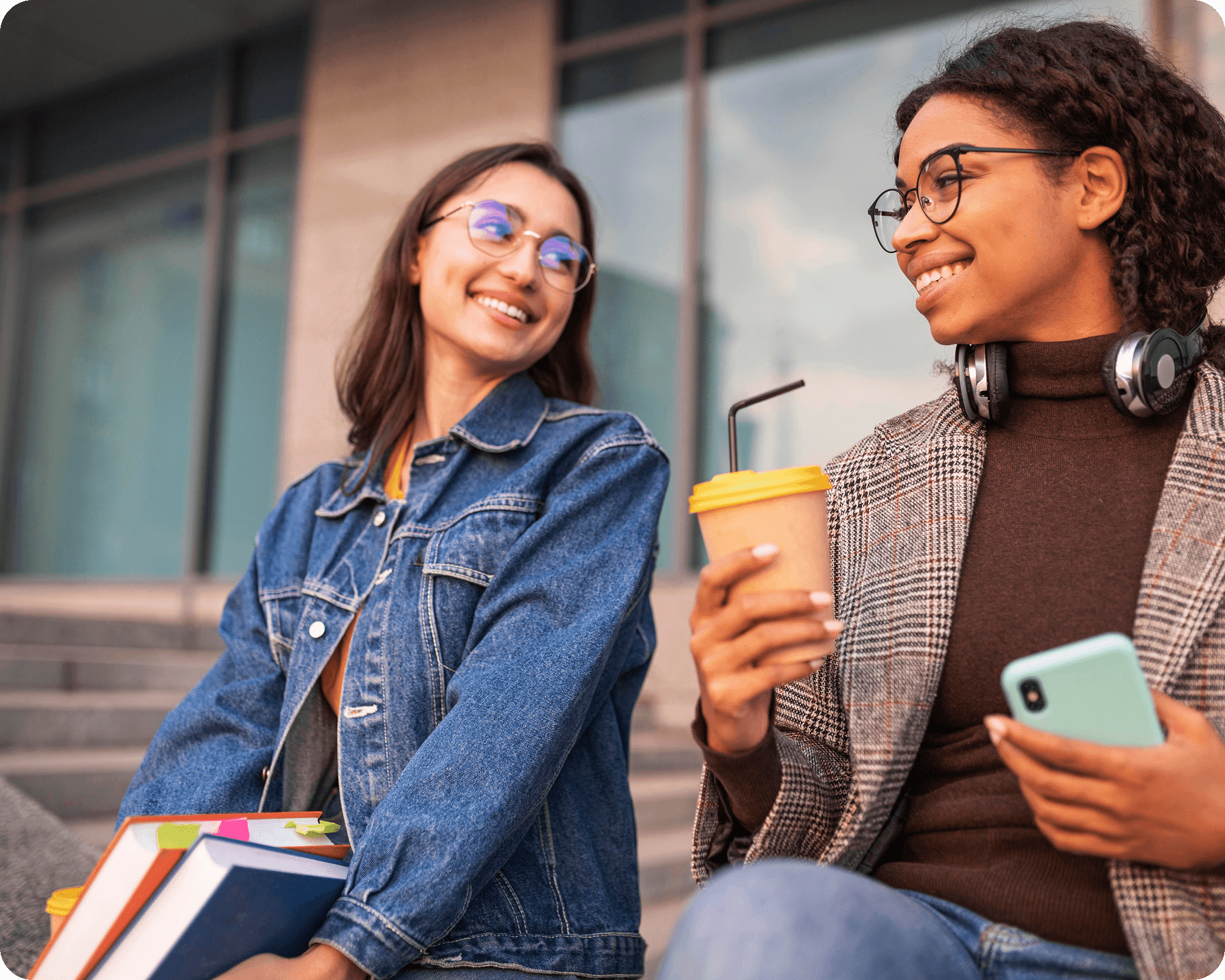 Two students sitting outside smiling together